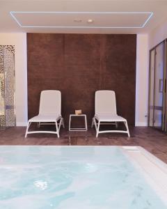 two white chairs sitting next to a swimming pool at Helios Benidorm in Benidorm