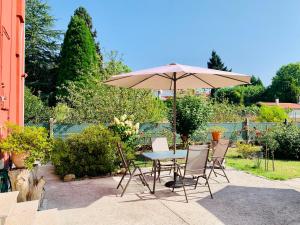 una mesa y sillas con una sombrilla en el patio en A Casa Vermella con jardín a 10 minutos de Santiago de Compostela, en Ortoño