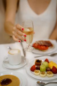 a woman holding a glass of wine next to a plate of food at Helios Benidorm in Benidorm