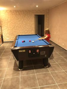 een jong kind dat pool speelt in een kamer met een pooltafel bij B&B DeSo in Zonnebeke
