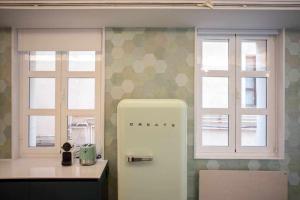 - un réfrigérateur blanc dans une cuisine avec 2 fenêtres dans l'établissement Espacio para 6 en el centro Wifi gratis, à Logroño