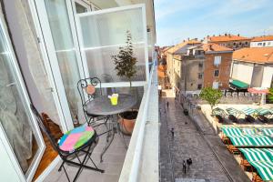 stół i krzesła na balkonie z oknem w obiekcie Zadar Old Town Apartments II w mieście Zadar