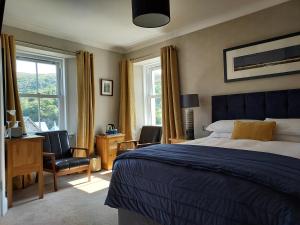 a bedroom with a bed and a desk and chairs at Seaview Guesthouse in Mallaig