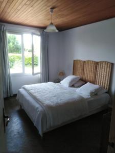 Schlafzimmer mit einem großen weißen Bett und einem Fenster in der Unterkunft Maison oléronaise avec la plage à pied et la piste cyclable au bout du jardin in Dolus d'Oléron