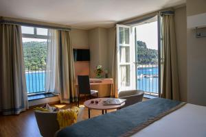 
a room with a bed, table, chair and a window at Grand Hotel Portovenere in Portovenere
