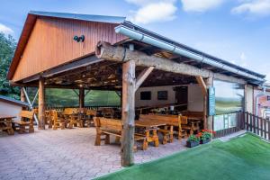 einem Holzpavillon mit Holztischen und Bänken in der Unterkunft Horsky hotel Rajska bouda in Malenovice