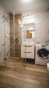 a bathroom with a shower and a washing machine at Apartament Marbud przy Aquaparku Reda in Rumia