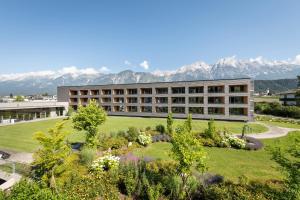 un bâtiment avec un jardin et des montagnes en arrière-plan dans l'établissement Der Reschenhof, à Mils bei Hall