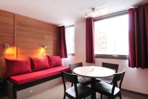 a living room with a red couch and a table at travelski home select - Résidence Les Glaciers in Mâcot La Plagne