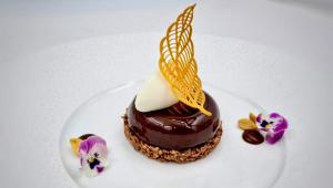 a chocolate dessert on a white plate with flowers at Crowne Plaza Limassol by IHG in Limassol