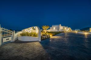 a night view of a villa with a white fence at Kyklos Villas - luxury villas with private pool in Karterados