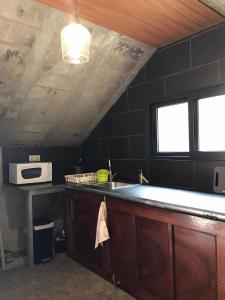 a kitchen with a sink and a microwave at A Casa Estrelícia-Dourada Garcês in São Vicente
