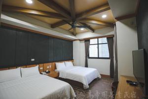 a bedroom with two beds and a flat screen tv at Gaodiyuan Tea B&B 高帝園茶業民宿 in Meishan