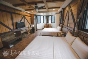 1 dormitorio con 2 camas, escritorio y TV en Gaodiyuan Tea B&B 高帝園茶業民宿, en Meishan