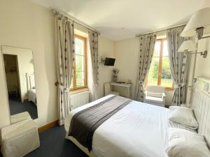 a bedroom with a large white bed and windows at Auberge Côté Rivière in Is-sur-Tille