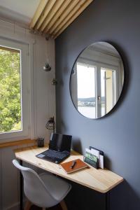 a desk with a laptop and a mirror on a wall at Appartement Vue Lac in Malbuisson
