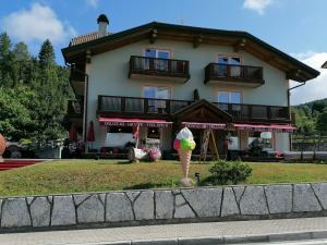 un gran edificio con una sombrilla delante de él en Giongo Residence - Appartamenti, en Lavarone