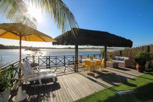 eine Terrasse mit Stühlen, Tischen und Sonnenschirmen in der Unterkunft Casa pé na areia na Praia de Genipabu by Carpediem in Extremóz