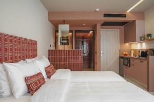 a bedroom with a large white bed and a kitchen at Pavo Art Hotel in Heraklio Town