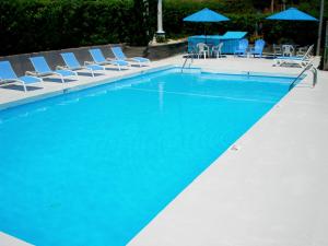 a swimming pool with blue chairs and umbrellas at GuestLodge in West Dennis