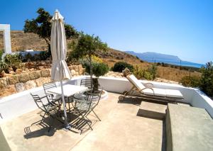a patio with a table and chairs and an umbrella at Domatia me Thea in Elafonisos