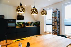 a kitchen with a wooden table and pendant lights at FeWo26 in Thale