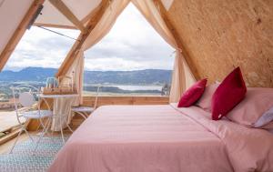 ein Schlafzimmer mit einem Bett und einem großen Fenster in der Unterkunft Andes Glamping in Guatavita