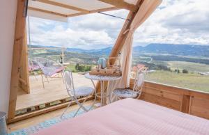 Habitación con balcón con sillas y mesa. en Andes Glamping, en Guatavita