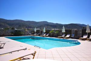 a swimming pool with chairs and umbrellas at Altis Hotel in Malia