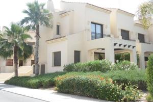 a large white house with palm trees and flowers at Roda Golf & Beach Resort. Townhouse, Poolside in Murcia
