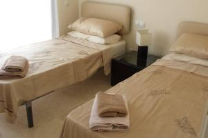 two beds in a room with towels on them at Roda Golf & Beach Resort. Townhouse, Poolside in Murcia