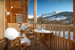 a balcony with a table and chairs and a large window at Chalet des Mômes - OVO Network in Le Grand-Bornand
