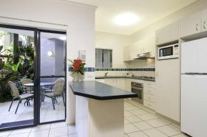 a kitchen with white appliances and a table and chairs at Bay Villas Resort in Port Douglas
