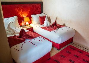 two beds in a room with red and white at Riad Romance in Marrakesh