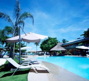 マラパスクア島にあるマラパスクア レジェンド ウォータースポーツ アンド リゾートのラウンジチェアとパラソル付きのスイミングプールを併設しています。