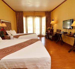 une chambre d'hôtel avec deux lits et une télévision à écran plat dans l'établissement Malapascua Legend Water Sports and Resort, à Malapascua