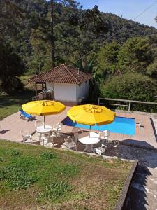 two yellow umbrellas and chairs next to a pool at Sitio Sao Jeronimo in Teresópolis