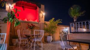 マラケシュにあるリヤド ロマンスの赤いライトが付いたテーブルと椅子が備わるレストラン