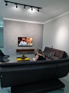 una mujer sentada en un sofá en una sala de estar en Casa nova, conforto total e perto da praia, en Peruíbe