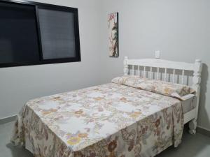 Un dormitorio con una cama con una manta encima. en Casa nova, conforto total e perto da praia, en Peruíbe