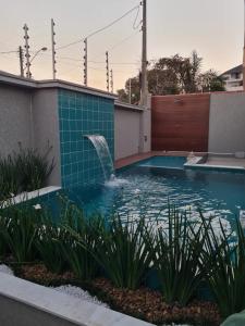 una piscina con una fuente en una casa en Casa nova, conforto total e perto da praia, en Peruíbe