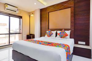 a bedroom with a large white bed with colorful sheets at FabHotel Eros 211 in Kolkata