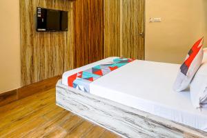 a bedroom with a bed with a television on a wall at FabExpress Quest in Kolkata