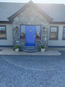 una porta blu di una casa con due piante di Wild Atlantic Breeze Guesthouse a Doolin