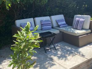 a couch and two chairs sitting on a patio at Duke of Monmouth penthouse luxury apartment, Lyme Regis, 3 bedroom, Hot tub, Garden, dog friendly in Lyme Regis