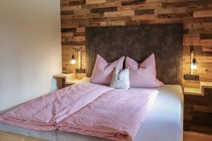 um quarto com uma cama com lençóis e almofadas cor-de-rosa em Apartment Steger 2 em Mittersill