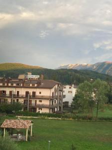 un grande edificio in un campo con montagne sullo sfondo di Appartamento Fiore Rocca a Rocca di Mezzo