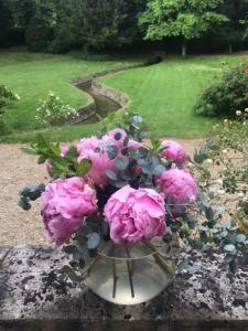 un vase rempli de fleurs roses sur une table dans l'établissement Propriété Les Ruisseaux, à Seine-Port