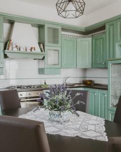 una cocina con armarios verdes y una mesa con flores. en Villa Santimone, en Éboli