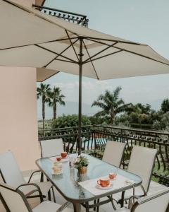 una mesa con sillas y una sombrilla en el balcón en Villa Santimone, en Éboli